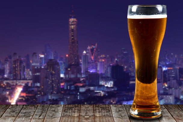 Bicchiere di birra su una città di legno di notte sfondo
. - Foto, immagini