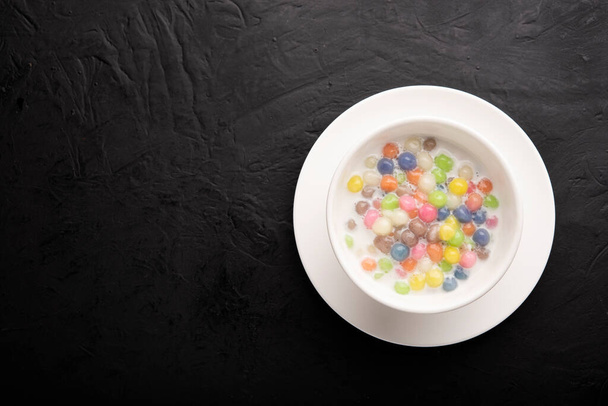 Тайські солодощі і барвисте м'яча борошно в білій чашці на темному столі Солодкі веселки, популярні і відомі тайські десерти, Bua Loy, Bua Loi, Pandan листя - Фото, зображення