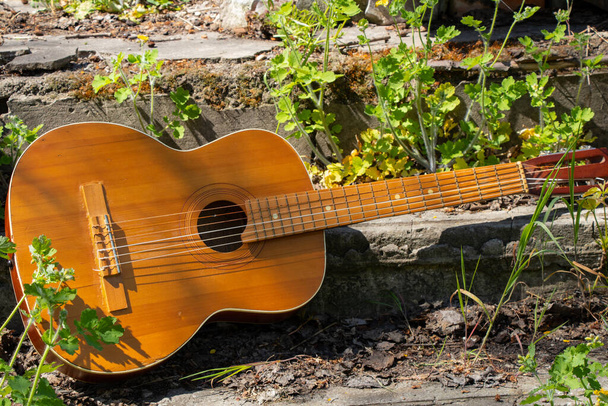 guitarra marrom de madeira encontra-se em uma estrada de pedra na rua na grama primavera
 - Foto, Imagem
