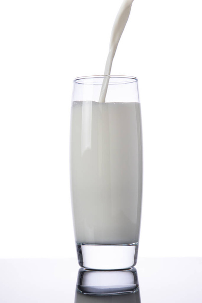 Wlewanie mleka do szklanki, izolowane na białym tle - Zdjęcie, obraz