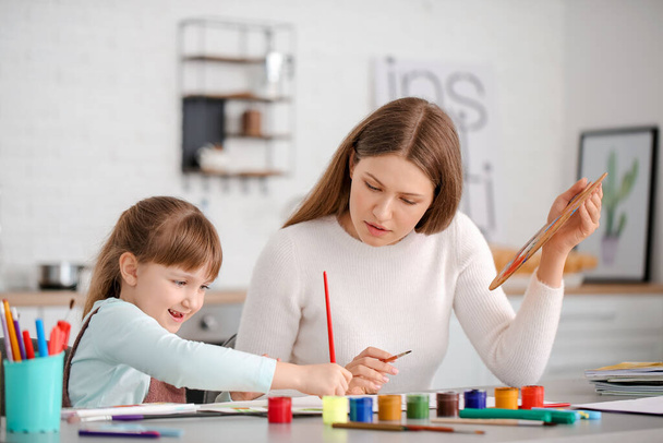 Учитель рисования дает частные уроки рисования маленькой девочке дома
 - Фото, изображение