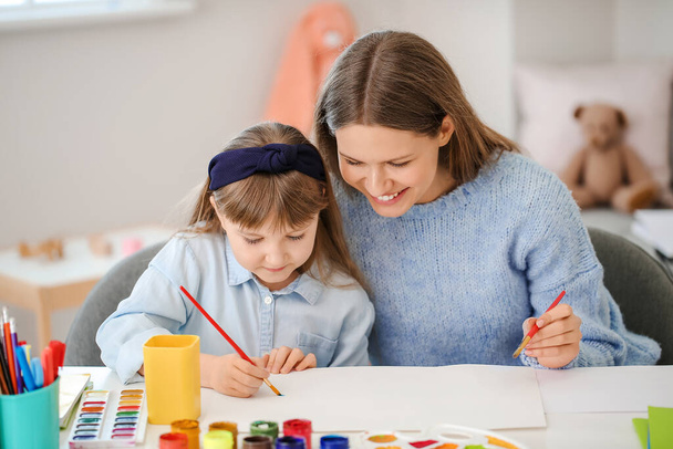 Учитель рисования дает частные уроки рисования маленькой девочке дома
 - Фото, изображение