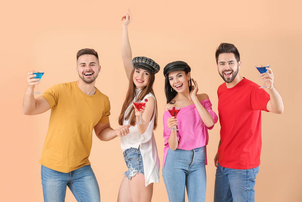 Счастливые молодые люди с коктейлями на цветном фоне
 - Фото, изображение