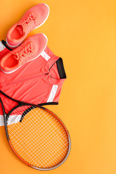 Sportbekleidung und Tennisschläger auf farbigem Hintergrund - Foto, Bild