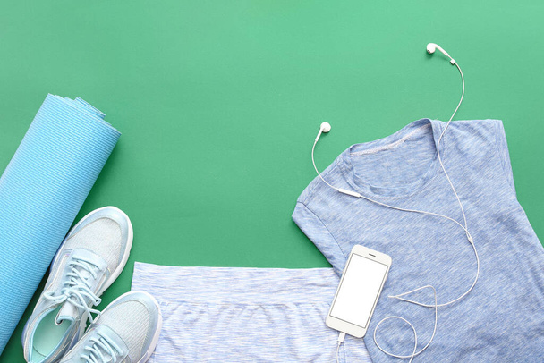 Sportbekleidung, Yogamatte und Handy auf farbigem Hintergrund - Foto, Bild