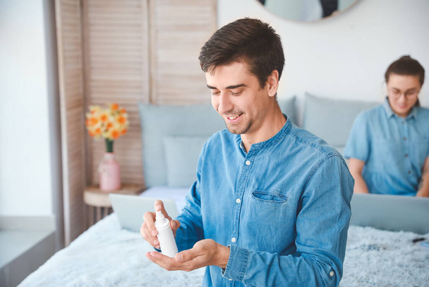 Homem aplicando desinfetante nas mãos em casa
 - Foto, Imagem