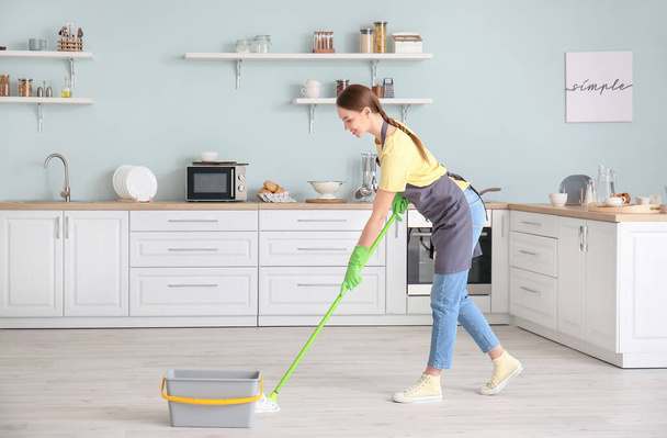 Young woman mopping floor in kitchen - Foto, Imagen