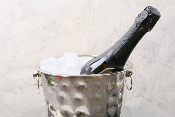 Bucket with ice and champagne on light background - Photo, Image