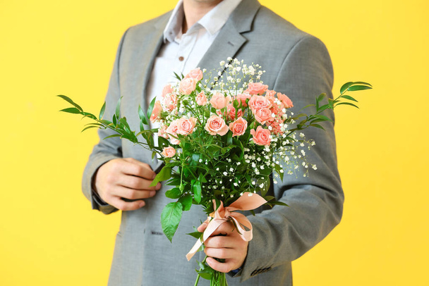 Renkli arka planda çiçek demeti olan yakışıklı bir adam. - Fotoğraf, Görsel