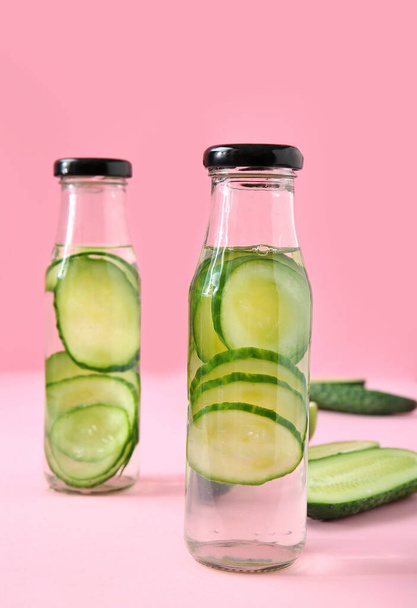 Bottles of cucumber infused water on color background - Valokuva, kuva