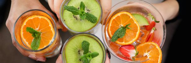 水のガラスに柑橘類の果実を閉じる。男性の手に飲み物をリフレッシュします。鮮やかな新鮮な果物のスライス. - 写真・画像