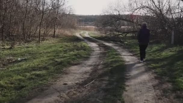Egy fiatal nő sétál a vidéki úton és telefonon beszél. - Felvétel, videó