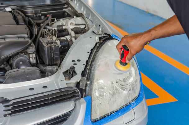 Les mécaniciens utilisent des outils à main pour polir les lampes à l'atelier de lavage de voiture
. - Photo, image