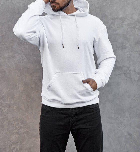 young man in white hoodie standing outdoors on gray background - Photo, Image