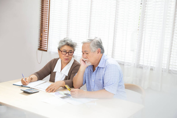 Aasian vanhempi pari vakavasti huolissaan laskettaessa laskuja maksaa kuukaudessa tai velkaa, Eläkkeellä vanhusten käsittelyssä lainaasiakirja, Raha ongelmia käsite
 - Valokuva, kuva