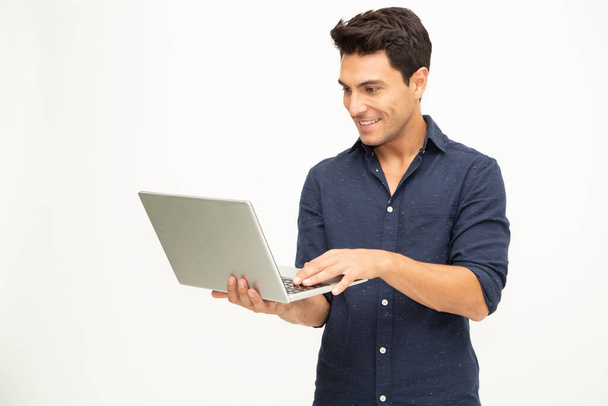 Retrato de un hombre emocionado sosteniendo ordenador portátil y celebrando el éxito sobre fondo blanco, Levantando brazos con una mirada de felicidad, Modelo masculino
 - Foto, Imagen