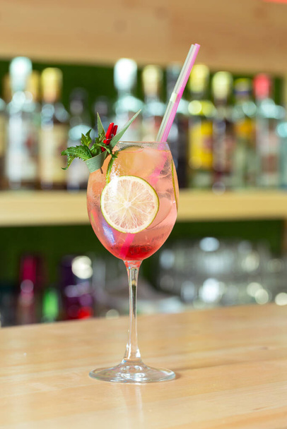 Glass of cocktail decorated with fruits at bar counter background. - Foto, Imagen