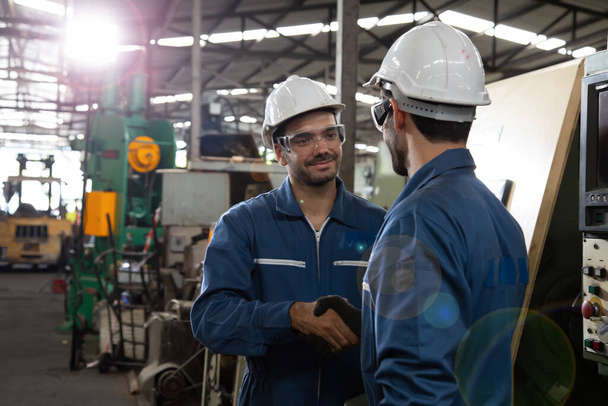 Schwerer Industriearbeiter in Handschuhen begrüßt sich mit Handschlag über Metallfabrik, Teamwork und Partnerschaftskonzept - Foto, Bild