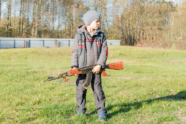 Mały chłopiec bawiący się zabawkowym pistoletem, w jesienny dzień we wsi - Zdjęcie, obraz