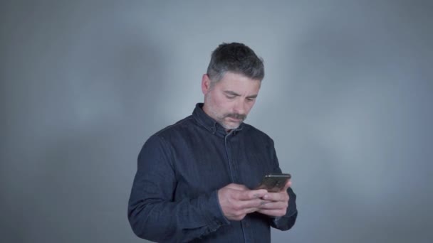 A man on the smartphone on a gray background - Materiał filmowy, wideo