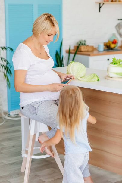 Embarazada rubia en la cocina en la mesa parses col verde
 - Foto, Imagen