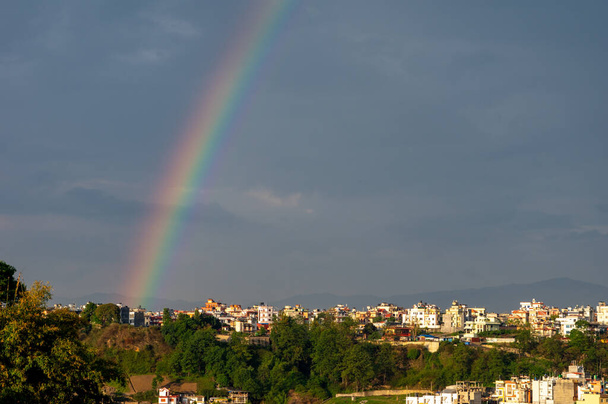 Un arco iris bellamente coloreado en el cielo contra las oscuras nubes de tormenta sobre Katmandú, Nepal
. - Foto, Imagen