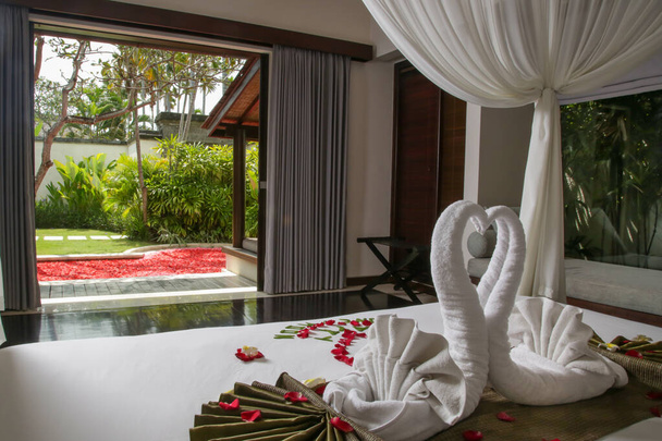 Luxury hotel bedroom interior with honeymoon decoration, Towel swans and rose flowers on the bed - Foto, Imagen