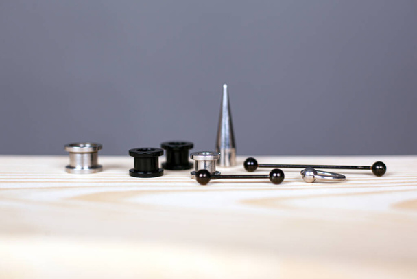 oorpiercing set. piercing accessoires op grijze achtergrond close-up - Foto, afbeelding