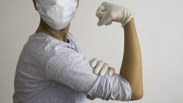 Mujer doctora con máscara quirúrgica y guantes de goma blanca en la posición de Rosie la Remachadora "Podemos hacerlo
!"  - Foto, Imagen