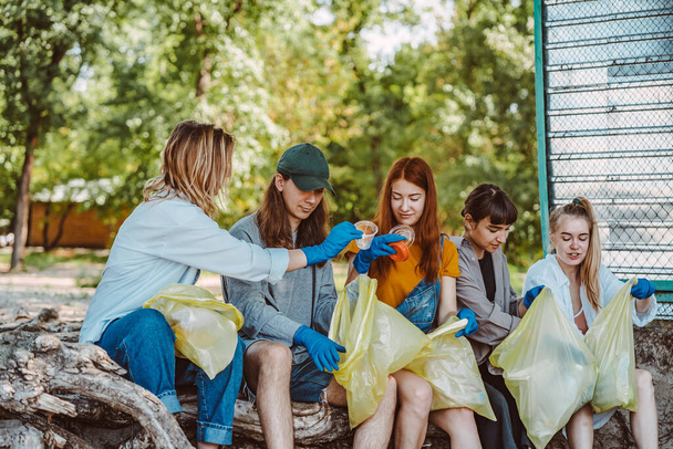 Group of activists friends collecting plastic waste at the park. Environmental conservation. - Photo, Image
