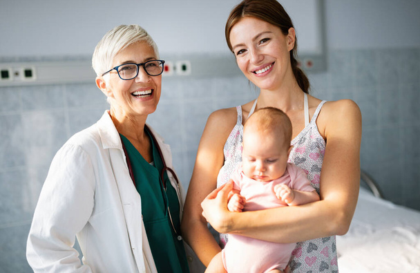 Pediatrician with happy mother and baby on examination in hospital. Heatlhcare, family, doctor concept. - Φωτογραφία, εικόνα