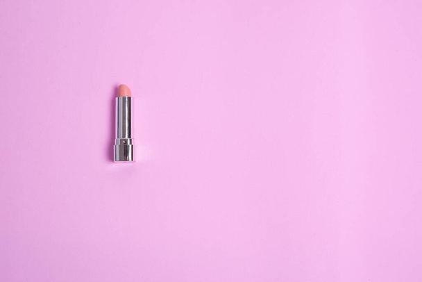 on a pink background lies a female pink lipstick - Фото, зображення