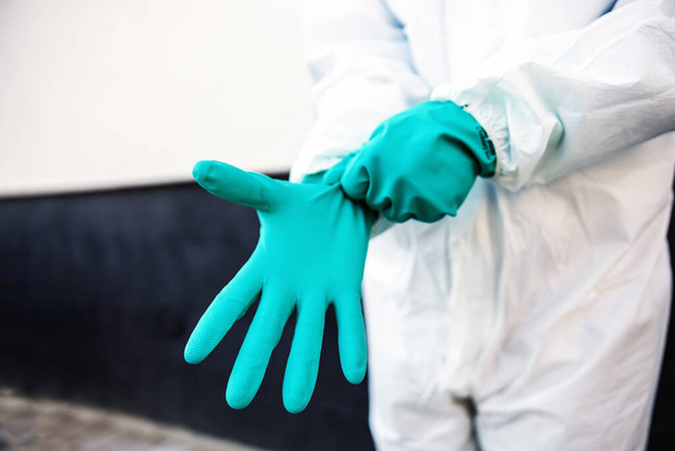Closeup of man in sterile uniform purring rubber gloves and preparing himself for sterilization from covid-19/ corona virus. - Photo, image