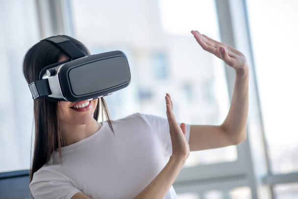 Dark-haired girl wearing vr headset and waving her hands - Фото, изображение