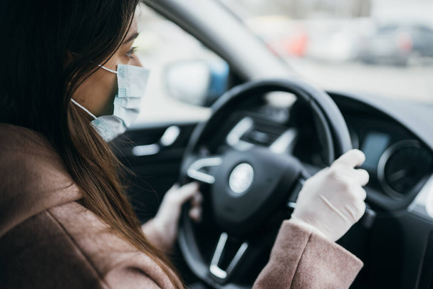 Молодая женщина в маске и перчатках за рулем автомобиля. - Фото, изображение