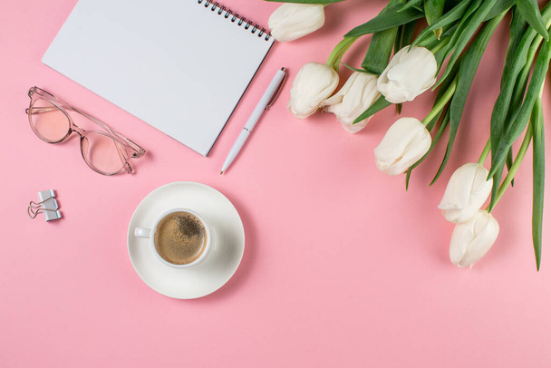 Concepto de mujer de negocios. Portátil tulipanes blancos, café y vasos sobre un fondo rosa
. - Foto, Imagen