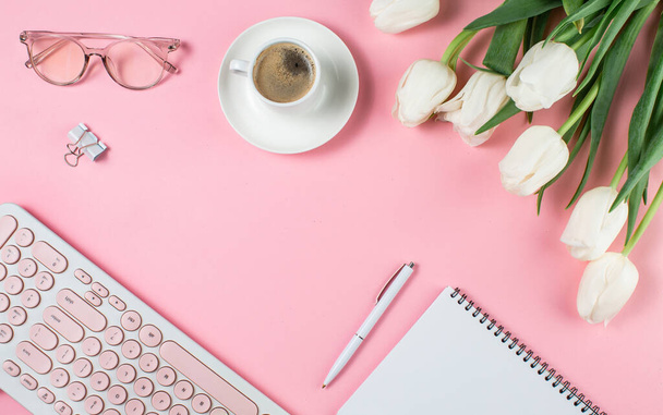 Concept de femme d'affaires. Ordinateur portable tulipes blanches, café et verres sur fond rose
. - Photo, image