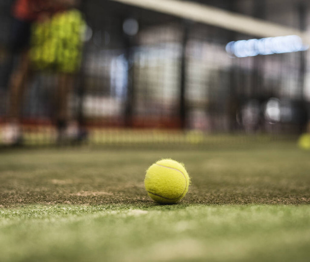paddle tennis ball in court. Defocused man in background training behind net - Photo, image