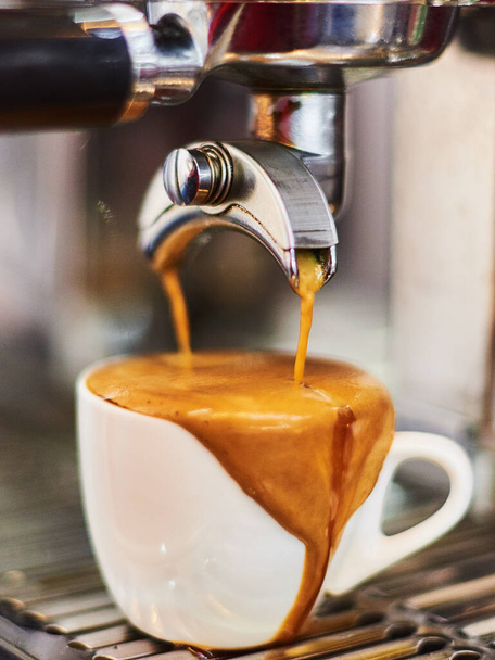 Espresso is poured into the Cup with the help of a coffee machine over the edge - Zdjęcie, obraz