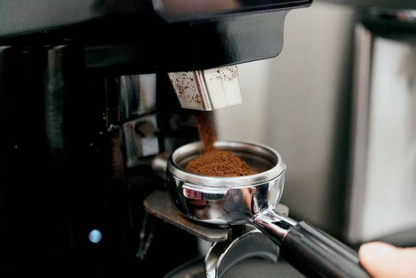 The process of automatic coffee grinding in a coffee grinder close-up. A handful of ground coffee in the holder - Fotografie, Obrázek