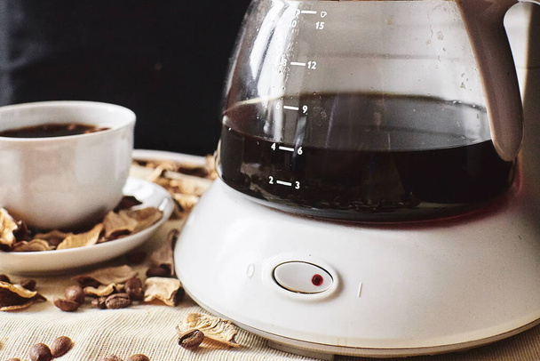 A vessel with black coffee half with a power button - Фото, изображение