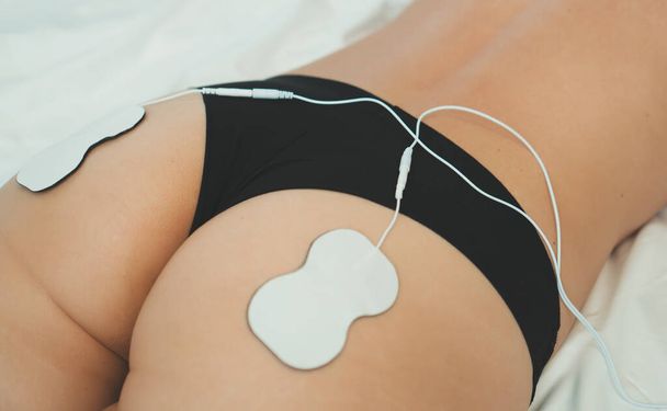 Corps de femme avec des électrodes sur les fesses. stimulation musculaire électrique
. - Photo, image