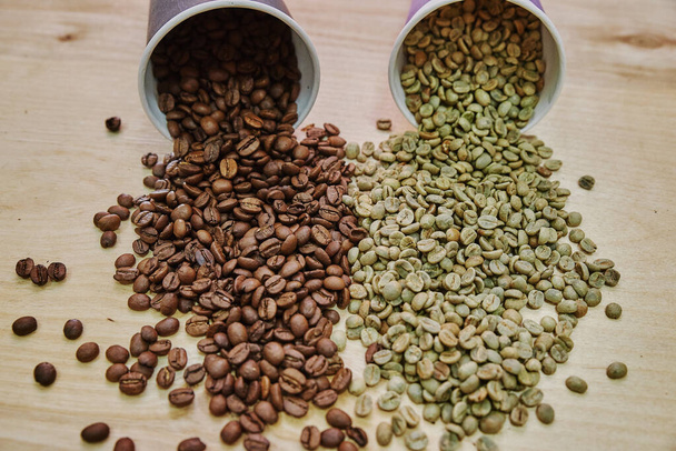 Coffee beans before and after roasting. Brown and green grains scattered on the table - Fotoğraf, Görsel