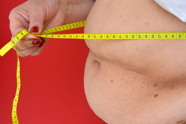 Woman measures a fat belly. Healthy lifestyles concept. Background to obesity - Photo, Image
