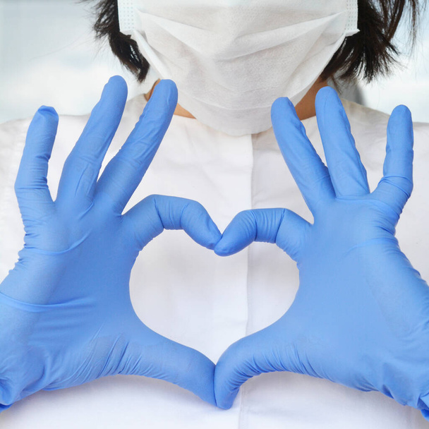 manos en guante de látex muestra el símbolo del corazón. Amar a nuestros profesionales médicos
. - Foto, Imagen