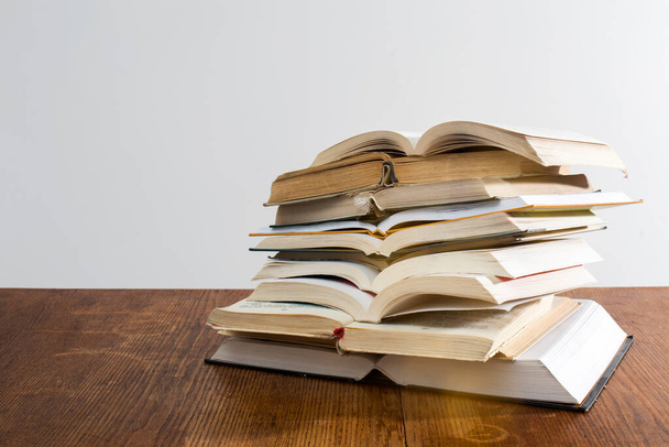 many stacks of educational open books for learning preparation for college exams on a wooden table on a white background. Self-education. On-line education in time of isolation - Foto, imagen