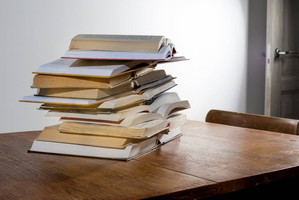 many stacks of educational open books for learning preparation for college exams on a wooden table on a white background. Self-education. On-line education in time of isolation - Фото, зображення