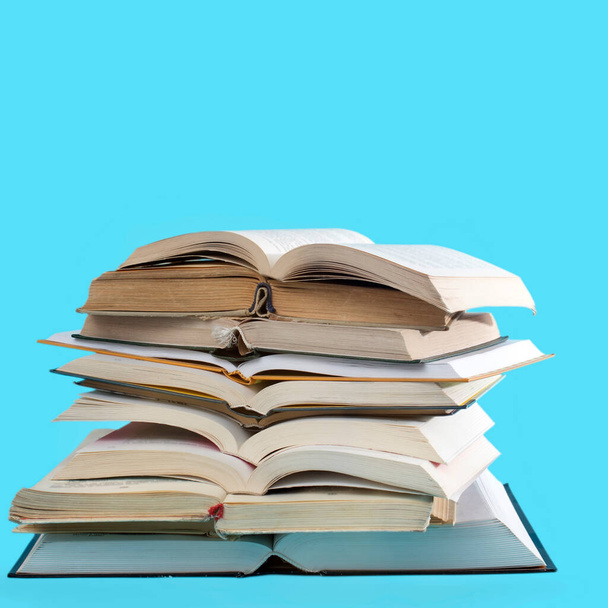 many stacks of educational open books for learning preparation for college exams on a blue paper craft background. Self-education. On-line education in time of isolation - Photo, image