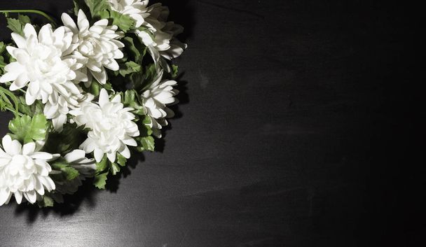 Símbolo funerario. Un ramo de flores blancas en el lado, fondo negro, espacio libre para el texto
. - Foto, Imagen