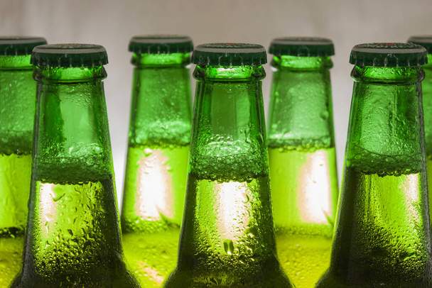 Часть зеленых бутылок пива в капельках конденсата на светлом фоне
. - Фото, изображение